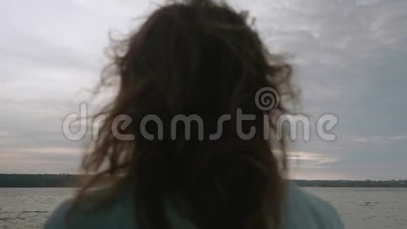 在水前的码头上深色头发的深色头发的后视图被分散天空和水的背景视频的预览图