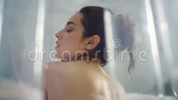 放松的女人在浴缸里洗脖子特写热女在洗澡时按摩身体视频的预览图