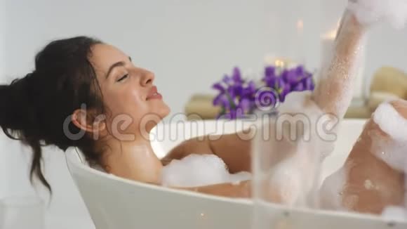 近距离放松的女人在泡沫浴中洗手在浴缸里休息的辣妹视频的预览图