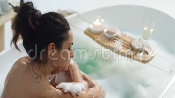 放松的女人用泡沫触摸皮肤性感少女洗澡时按摩身体视频的预览图