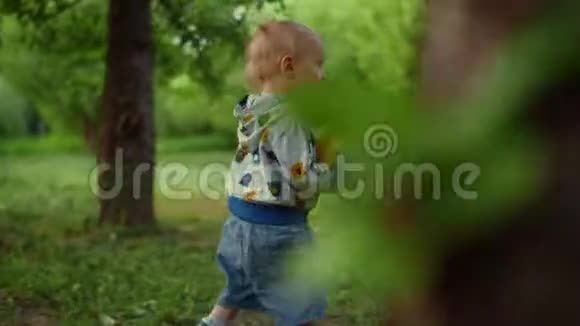 小男孩在森林里带球特写微笑幼儿男孩在户外跑步视频的预览图