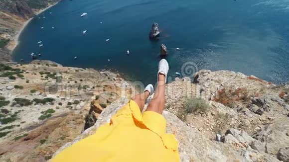 镜头放大了第一人称的视角那是一双棕色的女人腿穿着黄色的连衣裙坐在悬崖边自然令人惊叹视频的预览图