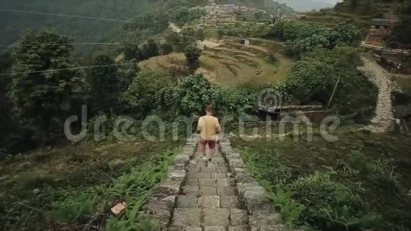 一个高加索年轻人从尼泊尔楼梯上跑下来跋涉景观梯田山丘山脉森林视频的预览图