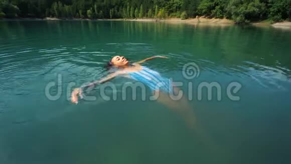 美丽苗条的幸福女人穿着蓝色泳装在炎热的阳光下在山湖放松游泳和享受淡水视频的预览图