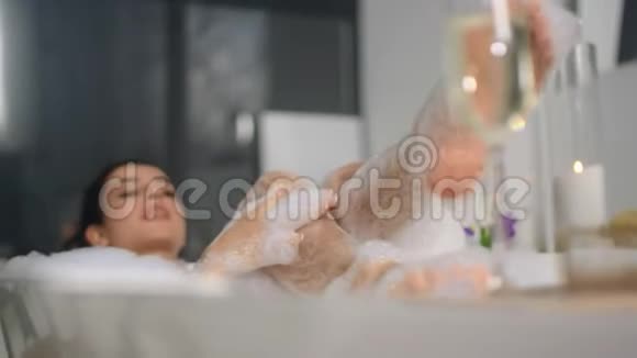 合上躺在泡沫浴缸里的性感女人在浴缸里洗腿的可爱女孩视频的预览图