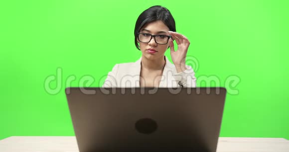 严肃的女士在工作场所使用笔记本电脑视频的预览图