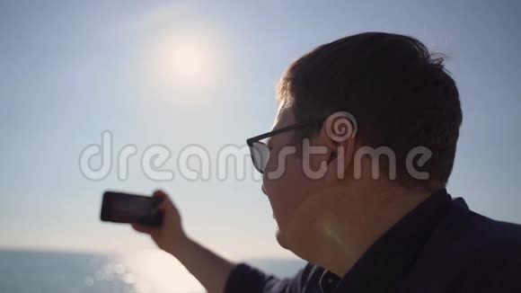 在海滩上用手机拍照的男人视频的预览图
