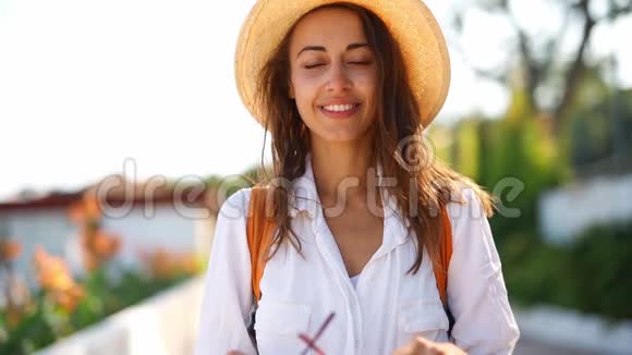 穿着白色衬衫和草色太阳帽的迷人女游客戴着太阳镜视频的预览图