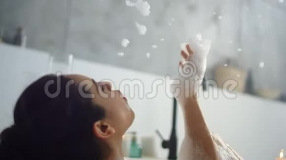 在浴室里关上放松的女人吹泡沫快乐的女孩玩泡沫视频的预览图