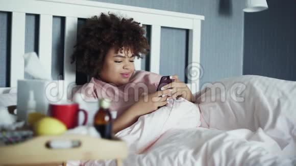 生病的非裔美国女孩在家里睡觉时用电话视频的预览图