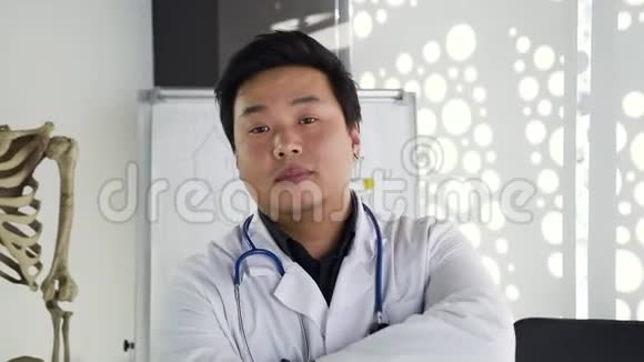 漂亮的年轻高技能亚洲医生身穿白色长袍手持听诊器在镜头前摆姿势的漂亮画像视频的预览图