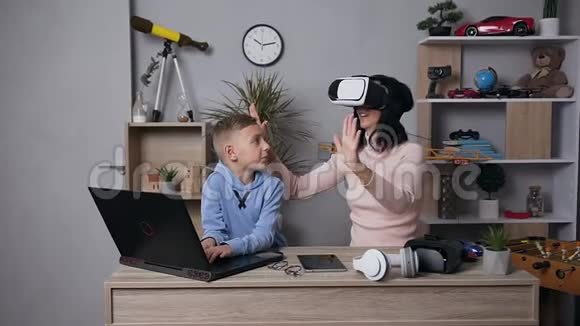 一个漂亮的黑发女人戴着虚拟3d眼镜和她微笑的10岁儿子在家使用电脑的正面景色视频的预览图