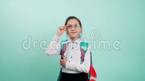 一个年轻的女学生一只手拿着眼镜架一个戴着蓝色背景眼镜的女学生的肖像A视频的预览图