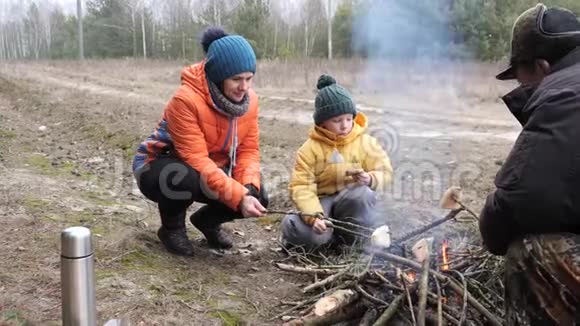 母亲和儿子在大自然的篝火上准备食物视频的预览图