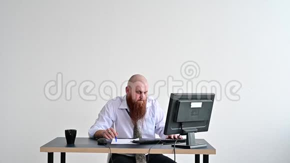 穿着衣服的疯狂商人在办公室里打破了他显示器上的键盘他在工作上有问题视频的预览图