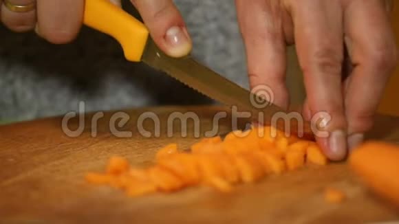 慢动作把胡萝卜切成小块放在木切割板上视频的预览图