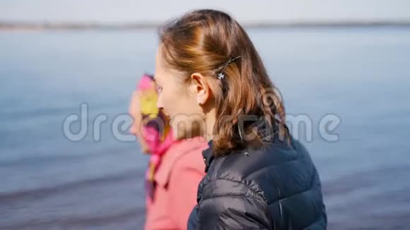一位年迈的妇女带着一个成年的女儿沿着海岸散步在一个秋天的日子里她愉快地交谈着笑着一个年轻人视频的预览图