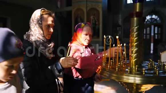 一位老年妇女在俄罗斯东正教教堂点燃蜡烛一位年迈的妇女带着女儿和孙女视频的预览图