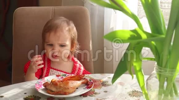 一个穿着漂亮裙子的小女孩拿着小块烤鸡放进嘴里幼儿宝宝吃鸡肉视频的预览图