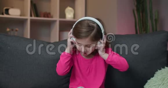 小女孩听无线耳机音乐有趣的小女孩跳舞唱歌和移动到节奏孩子视频的预览图
