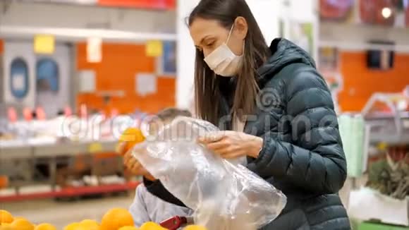 带着戴着医用口罩的小女孩在超市买橘子视频的预览图