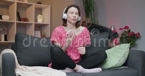 迷人的女人带着耳机在智能手机里听音乐跳舞戴着耳机的女孩视频的预览图