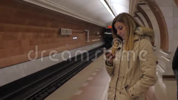 冬装女士候车站台地铁使用智能手机视频的预览图