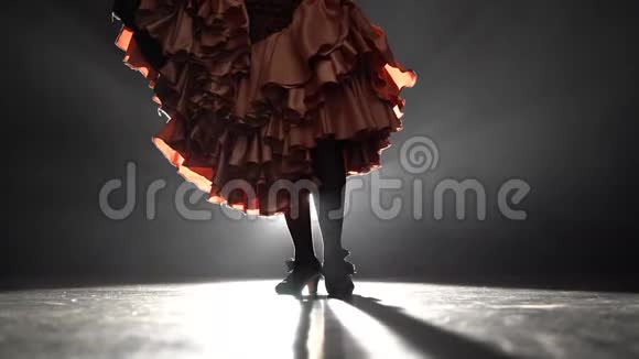 弗拉门戈女孩的腿在跳踢踏舞从后面的光烟雾背景特写视频的预览图