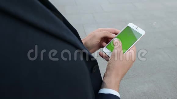 在城市街道上使用手机的商人工人在外面滚动智能手机视频的预览图
