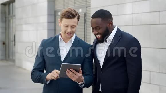 两位快乐的商人在现代城市读数字平板电脑的好消息视频的预览图