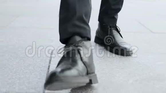 穿着黑鞋上班的商人男子双腿行走在城市道路上视频的预览图
