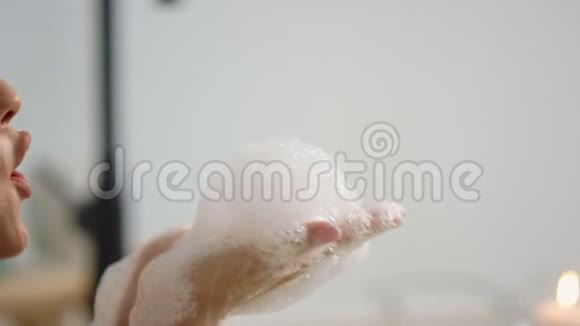 近距离放松的女人在洗澡时洗手臂侧面看可爱的女孩吹泡沫视频的预览图