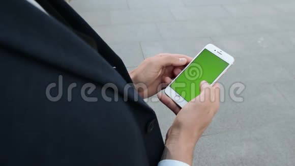 商人在街上用智能手机打字企业家在外面打电话视频的预览图
