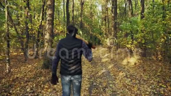 一个人拿着斧头走在秋天的树林里视频的预览图