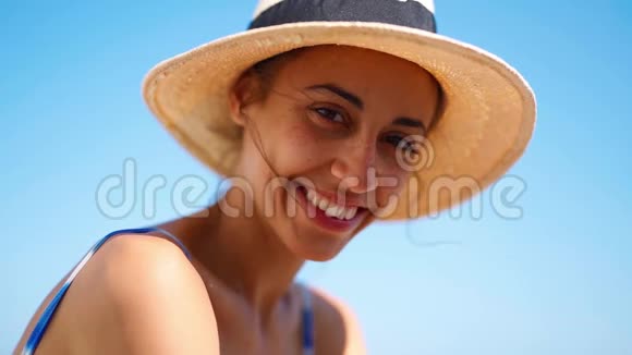 蓝天背景下戴草帽的漂亮晒黑女人的特写脸视频的预览图