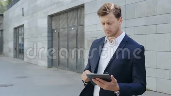 商人在街上做平板电脑在街上等合伙人的经理视频的预览图