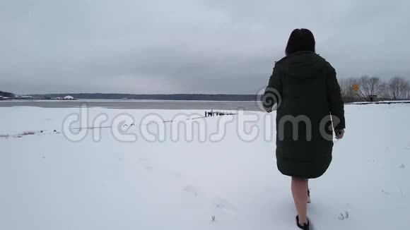 白种人深色皮肤走在地面上池塘附近积雪覆盖她穿着深色外套然后脱下只出现在视频的预览图