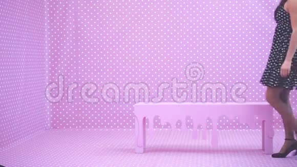 一位身材瘦削的黑发女孩头上戴着皮钉坐在粉红色的长凳上抚摸着她美丽的波尔卡舞视频的预览图
