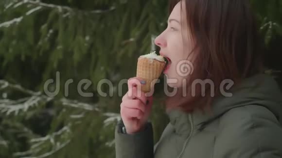 穿绿色外套的女人享受着冰淇淋她微笑着享受甜点夏天在寒冷的冬天吃视频的预览图