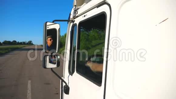 卡车司机戴着太阳镜在移动汽车的左侧镜子里反射男子驾驶卡车通过视频的预览图