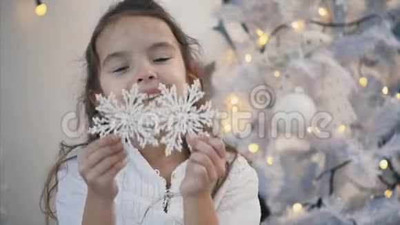 小女孩玩圣诞树雪花的特写视频把她的眼睛藏在后面视频的预览图