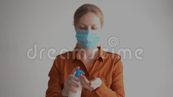 预防冠状病毒戴面具的女人用防腐剂处理双手视频的预览图