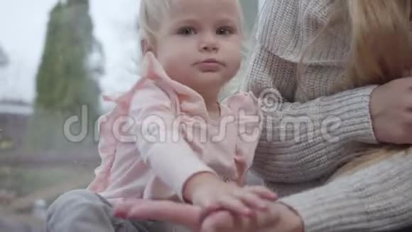 白人儿童拍手的肖像可爱的女婴坐在低矮的窗台上玩她视频的预览图