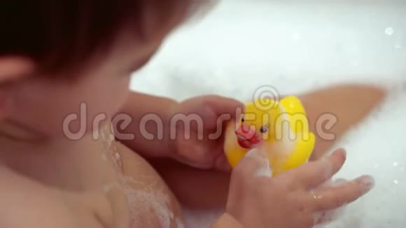用泡沫和黄色橡胶鸭洗澡的女婴视频的预览图