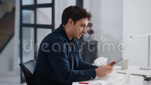 生病的商人在办公室得流感病人在室内笔记本电脑附近打喷嚏视频的预览图