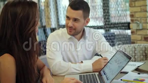 分享他们的想法当男人坐在办公室的休息区附近时微笑着年轻的女人用笔记本电脑工作视频的预览图