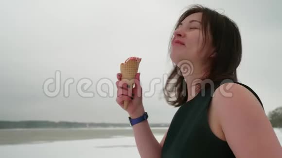 冬天穿着黑裙子的布鲁内特在外面吃冰淇淋开心地笑着对比概念完善和完善视频的预览图