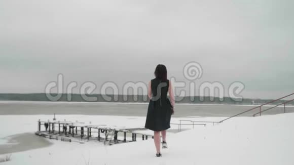 从后景可以看到黑发女人穿着一件黑裙子去池塘她停下来把自己吸出来取暖慢慢视频的预览图