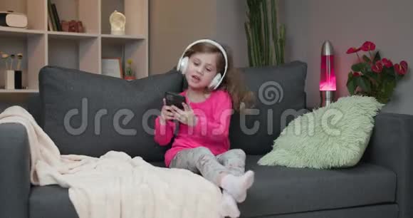 可爱的快乐小女孩听音乐无线耳机有趣的小女孩跳舞唱歌和律动视频的预览图