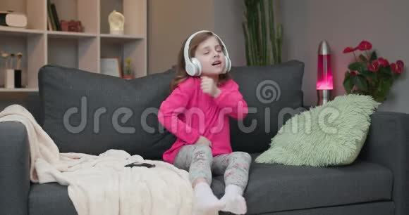 小女孩戴着无线耳机跳舞唱歌移动到节奏戴着耳机的小女孩孩子视频的预览图